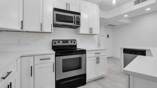 a kitchen with white cabinets stainless steel appliances and sink