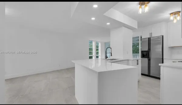 a large white kitchen with a sink and refrigerator
