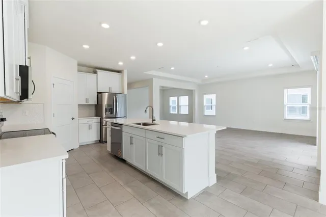 a large kitchen with stainless steel appliances lots of white cabinets