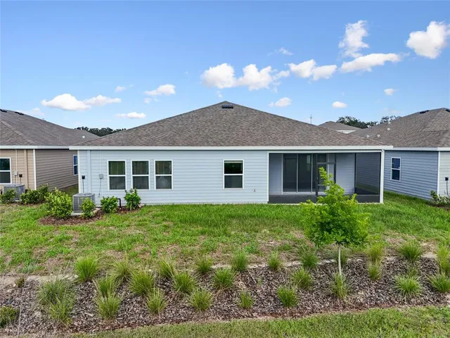a view of a yard in front of a house with plants and large trees