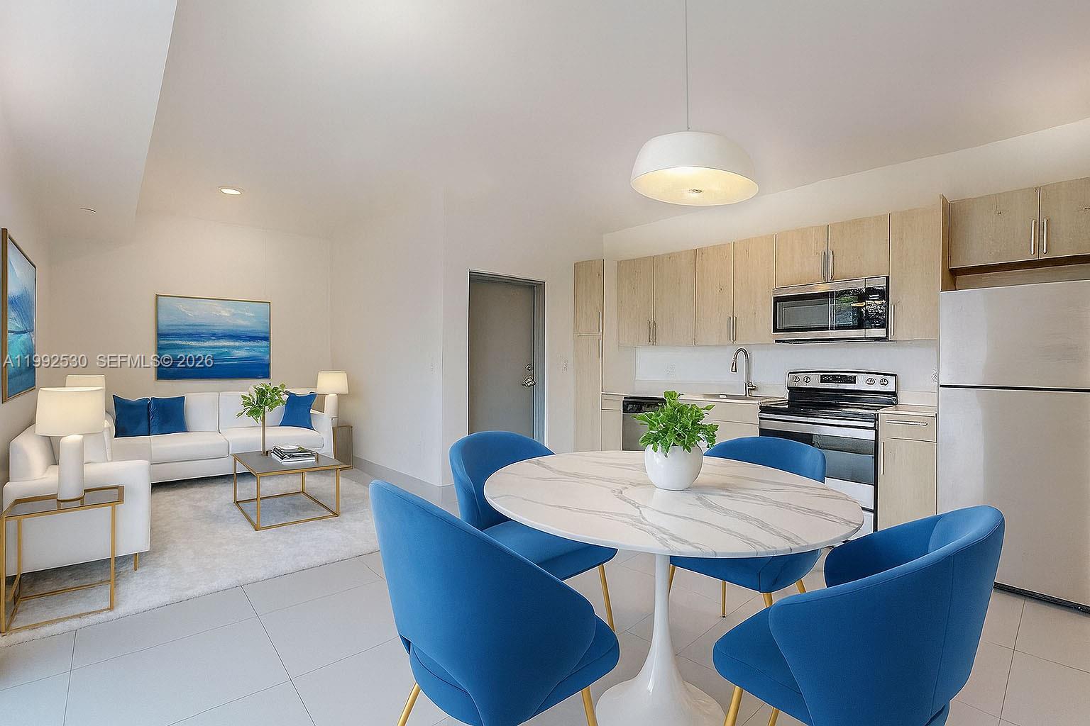 519 Southwest 5th Avenue, Unit 203 Miami, FL 33130 - Photo 5 of 26 a kitchen with stainless steel appliances granite countertop a dining table chairs stove refrigerator and microwave