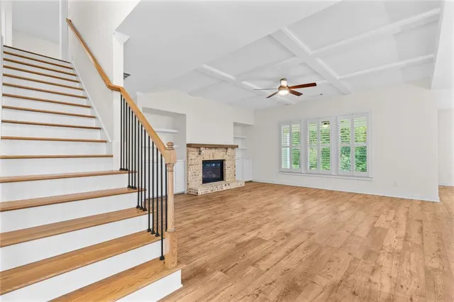 a view of an empty room with wooden floor fireplace and a window