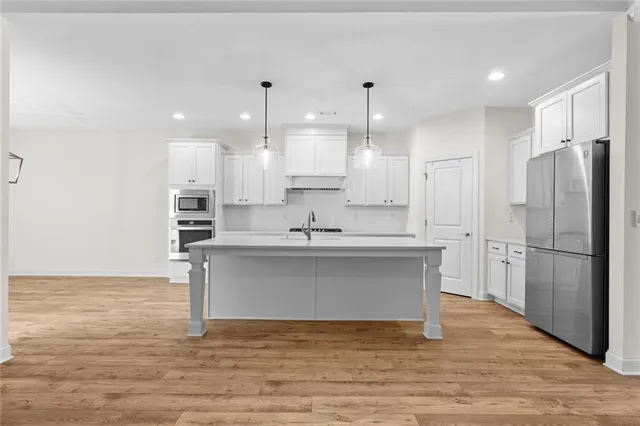a view of kitchen with kitchen island stainless steel appliances a sink and a refrigerator