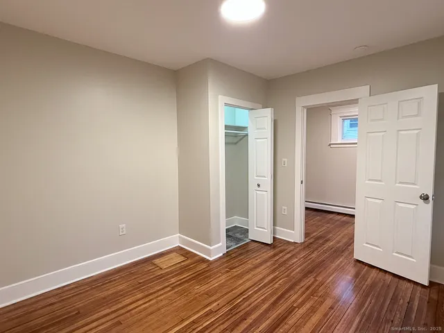 an empty room with wooden floor & closet area