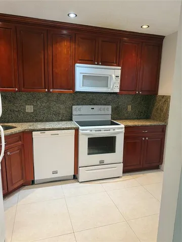 a kitchen with granite countertop a stove top oven and cabinets