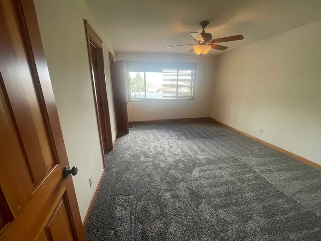 an empty room with windows and fan