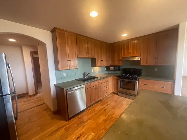 a kitchen with stainless steel appliances granite countertop a stove a sink and a refrigerator