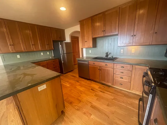 a kitchen with stainless steel appliances granite countertop a sink refrigerator and cabinets