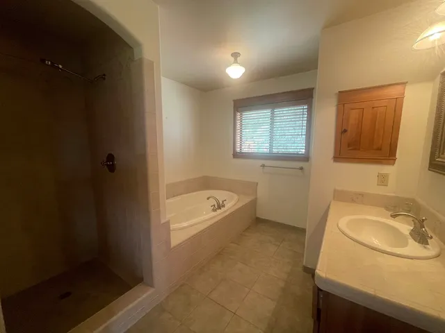 a spacious bathroom with a granite countertop sink a mirror bathtub and shower