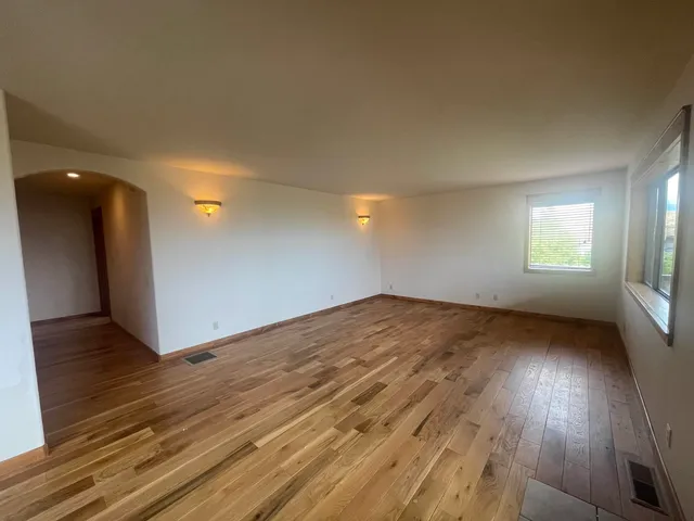 an empty room with wooden floor and windows