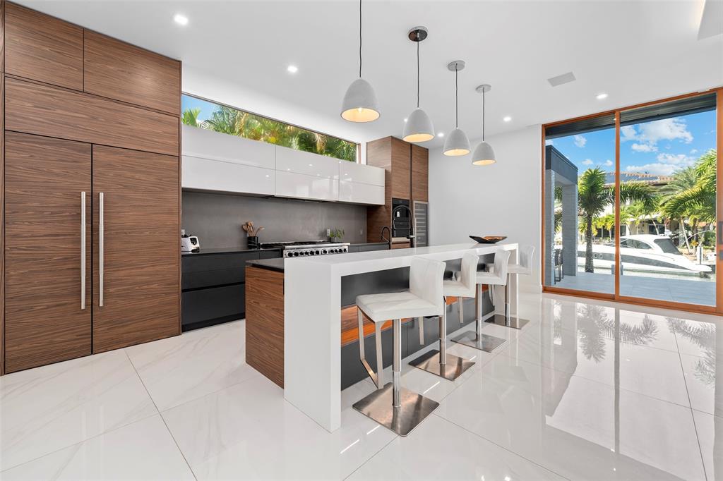 2631 Northeast 48th Court Lighthouse Point, FL 33064 - Photo 16 of 74 a kitchen with stainless steel appliances kitchen island granite countertop a stove a sink a refrigerator and a wooden cabinets