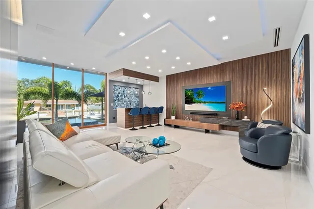 a kitchen with stainless steel appliances kitchen island granite countertop a sink a stove and a flat screen tv