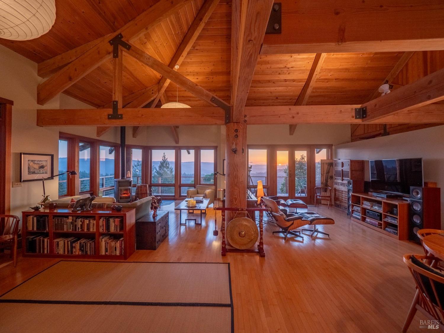 10951 Big Meadow Road Philo, CA 95466 - Photo 3 of 46 The architecture is rich with exposed wooden beams, high ceilings, and warm natural light that fills the open space. Everything in the room whispers comfort, care, and intentional living. But what really makes the scene unforgettable is the sunset spilling in through the windows.