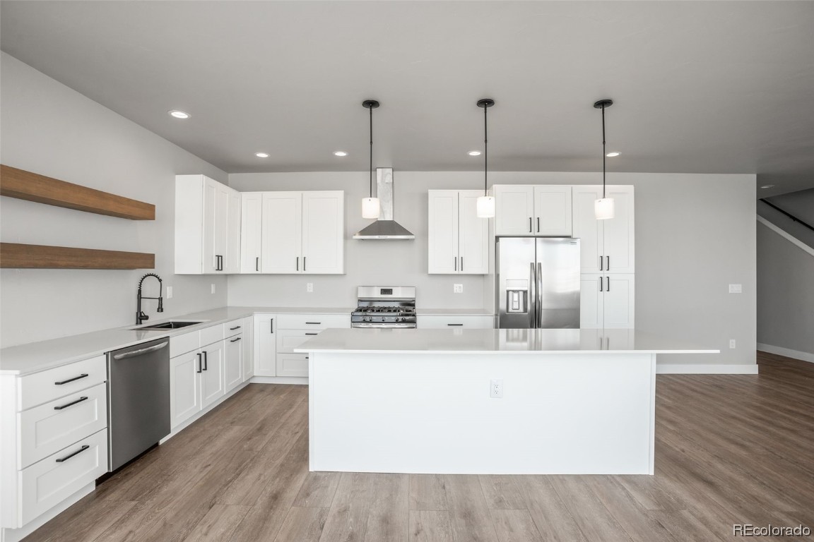 932 Dry Creek Road Hayden, CO 81639 - Photo 5 of 24 a large kitchen with stainless steel appliances kitchen island a stove a sink dishwasher a refrigerator and white cabinets with wooden floor
