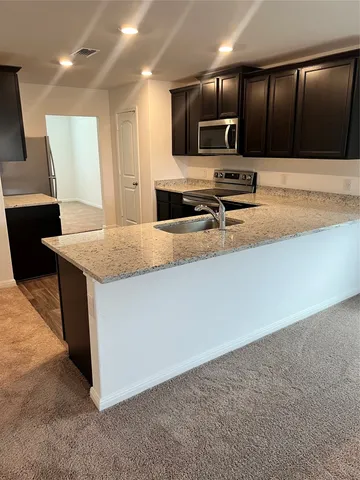 a kitchen with a sink a counter top space cabinets and stainless steel appliances