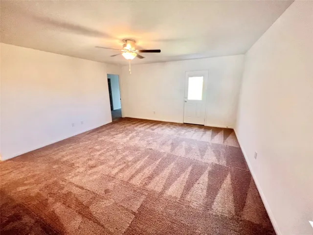 an empty room with a chandelier fan and windows