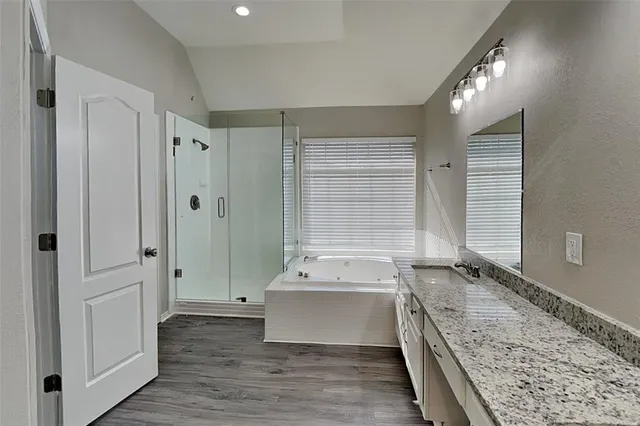 a bathroom with a tub a sink and a large mirror