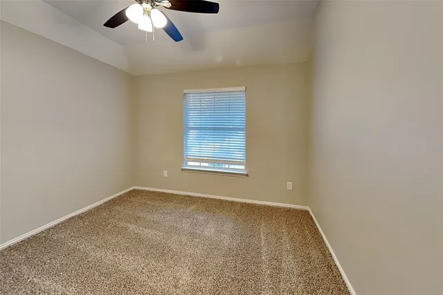 an empty room with a chandelier fan and windows