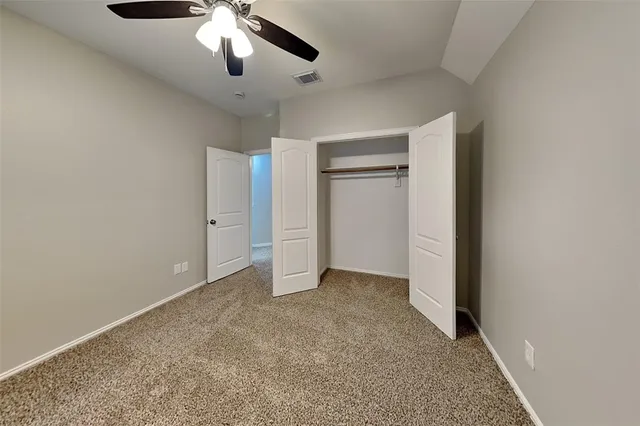 a view of an empty room and chandelier fan