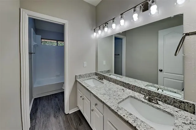 a bathroom with a granite countertop double vanity sink and mirror