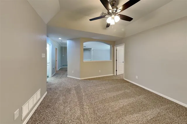 an empty room with chandelier fan and windows