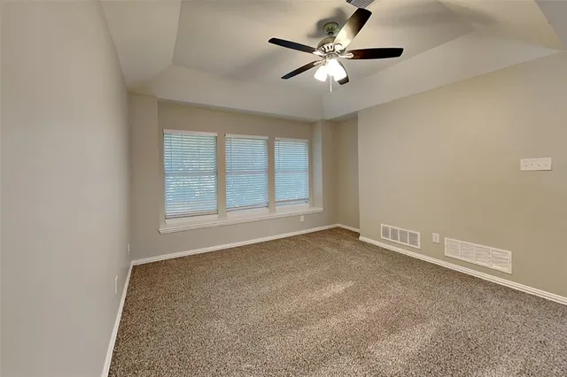 an empty room with chandelier fan and windows