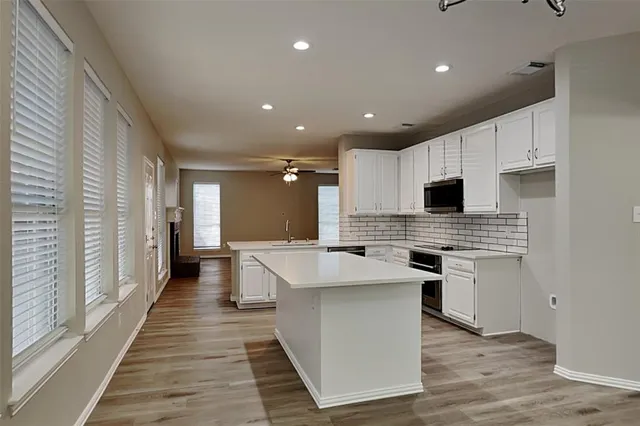 a kitchen with stainless steel appliances kitchen island granite countertop a stove top oven a sink and a refrigerator