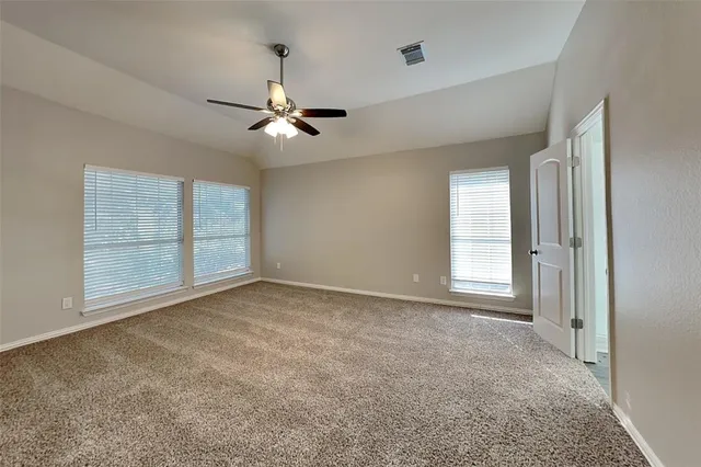 an empty room with chandelier fan and windows