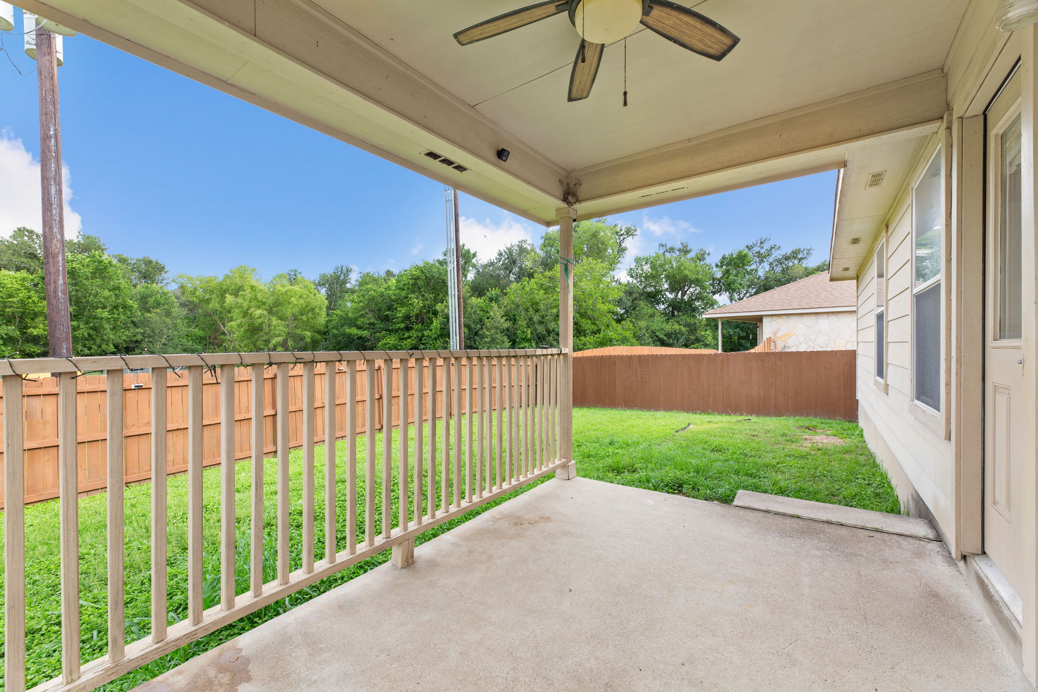 12601 Waynespur Lane Elgin, TX 78621 - Photo 34 of 38 A well-maintained wooden fence encloses a lush yard, offering privacy for the covered patio.