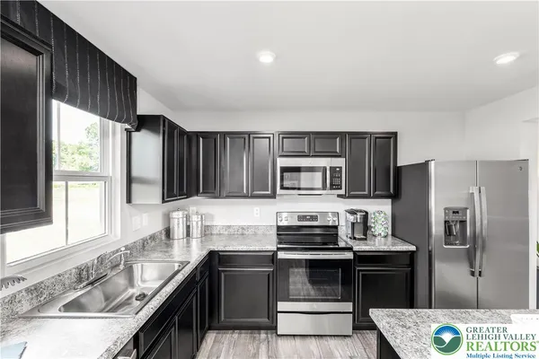 a kitchen with stainless steel appliances kitchen island granite countertop a sink stove and refrigerator
