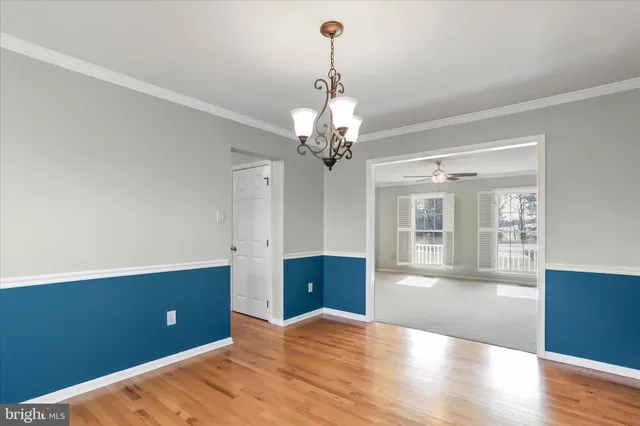 a view of a livingroom with a chandelier fan and wooden floor