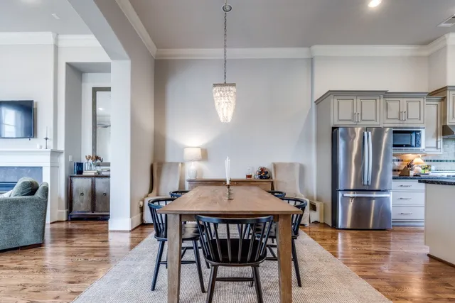 a kitchen with stainless steel appliances granite countertop a dining table chairs refrigerator and a stove