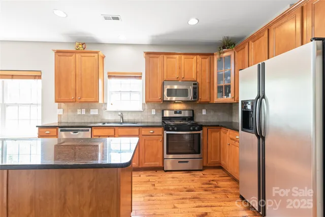 a kitchen with granite countertop a refrigerator stove top oven and sink