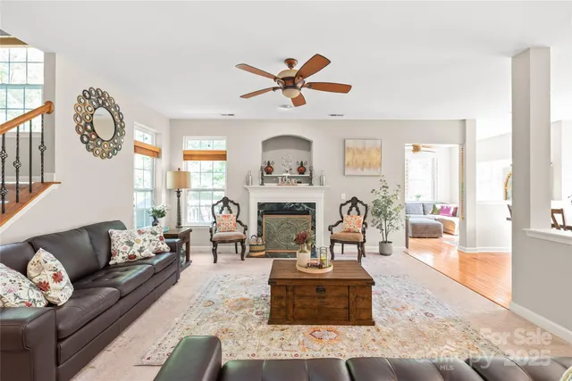 a living room with furniture a fireplace and a large mirror with wooden floor