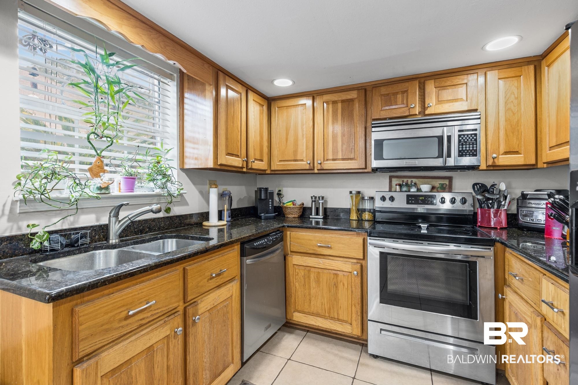 114 Du Rhu Drive, Unit A Mobile, AL 36608 - Photo 5 of 14 Kitchen with stainless steel appliances, wood finish cabinetry, dark stone countertops, light tile patterned floors, and recessed lighting