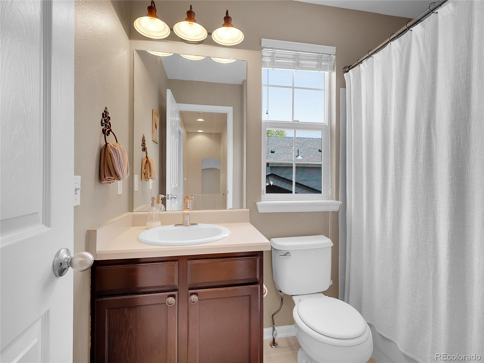 1234 Riddlewood Lane Highlands Ranch, CO 80129 - Photo 18 of 25 a bathroom with a toilet a sink a mirror a vanity and window
