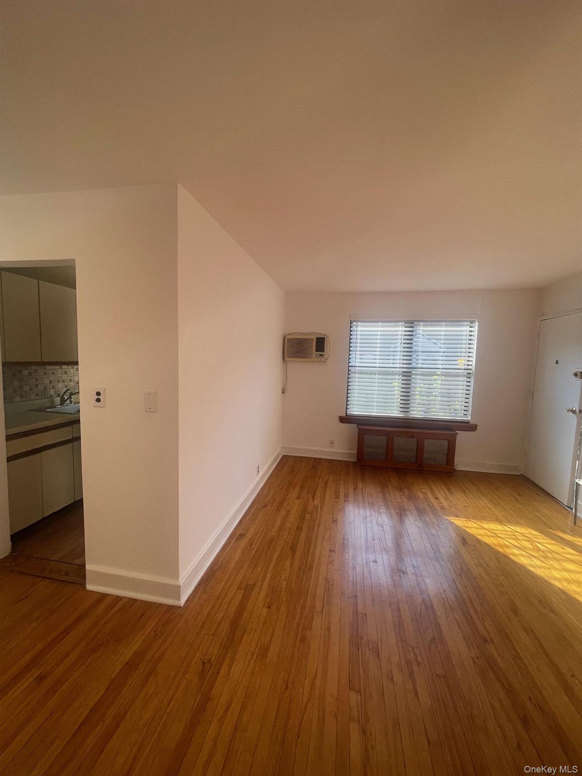 196-61 69th Avenue, Unit 1 Queens, NY 11365 - Photo 10 of 13 an empty room with wooden floor cabinet and windows