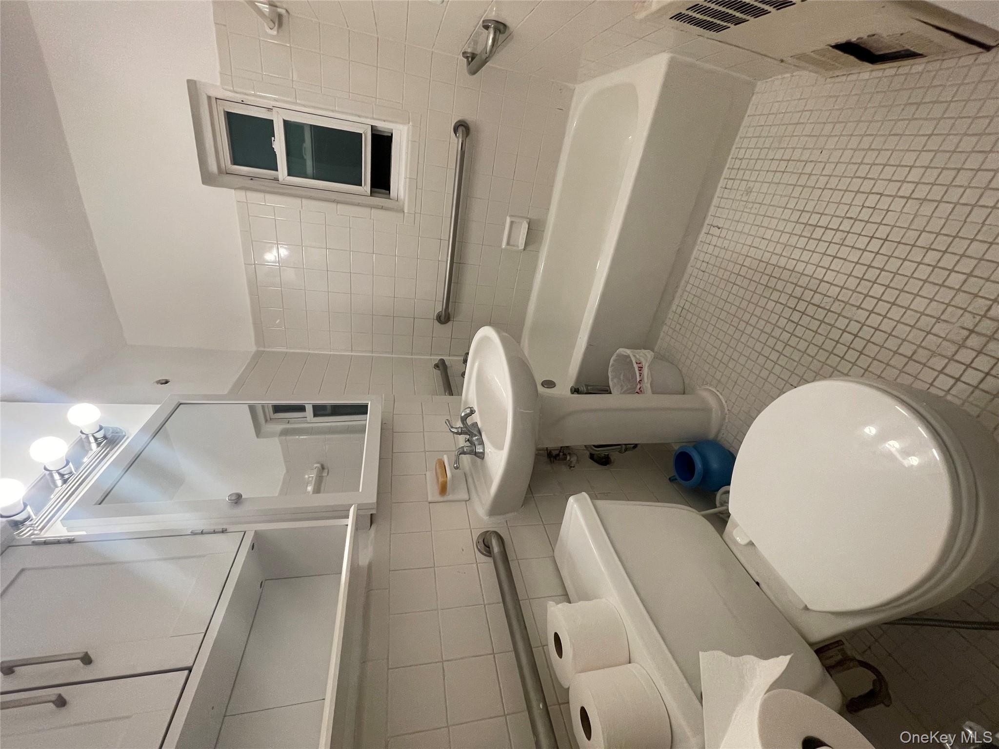 196-61 69th Avenue, Unit 1 Queens, NY 11365 - Photo 3 of 13 a bathroom with a sink a toilet and a mirror