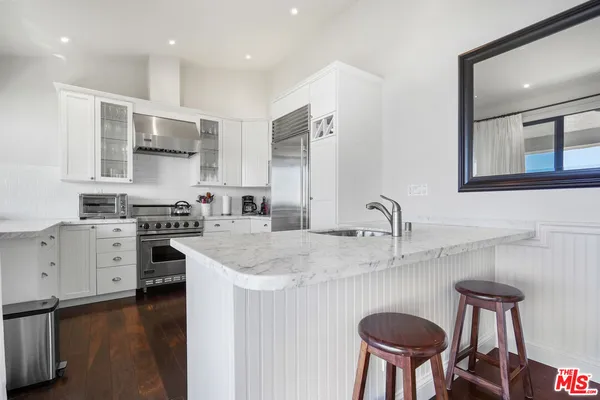 a kitchen with stainless steel appliances granite countertop a sink a stove and chairs