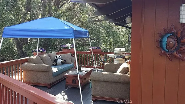 a view of a patio with couches table and chairs under an umbrella with a small yard