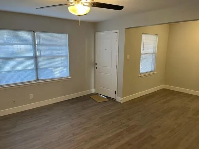 a view of an empty room with a window and wooden floor