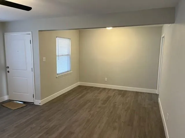 a view of an empty room with wooden floor and a window
