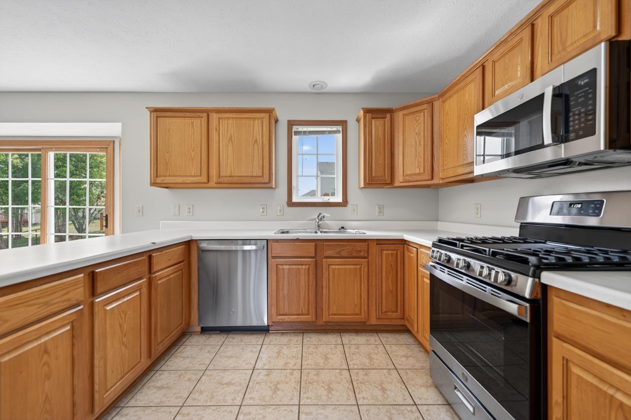 676 Elberon Way Roscoe, IL 61073 - Photo 12 of 30 a kitchen with stainless steel appliances granite countertop a stove a sink and a microwave