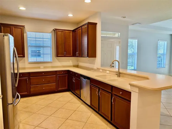 a kitchen with stainless steel appliances granite countertop a refrigerator a stove and a sink with wooden cabinets