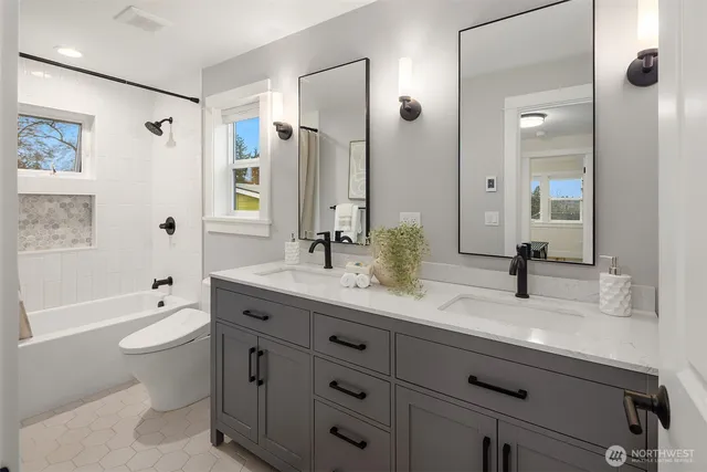 a bathroom with a granite countertop sink toilet mirror and bathtub