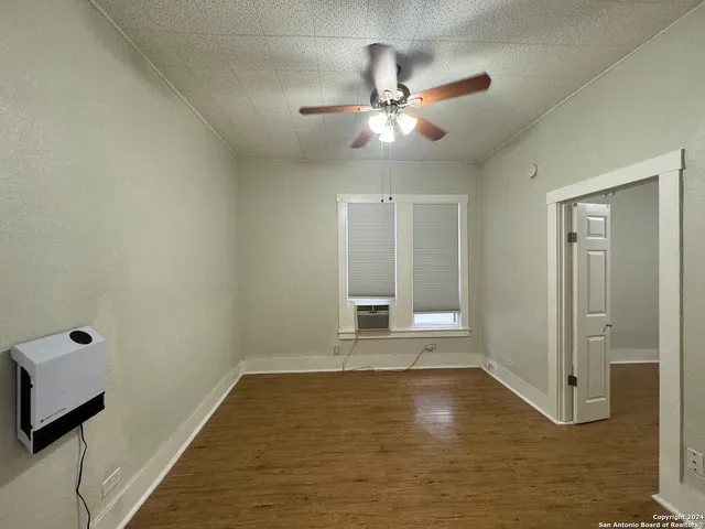 a view of an empty room with window and wooden floor