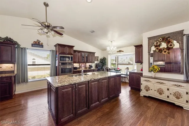 a large kitchen with stainless steel appliances granite countertop a stove refrigerator and a view of living room