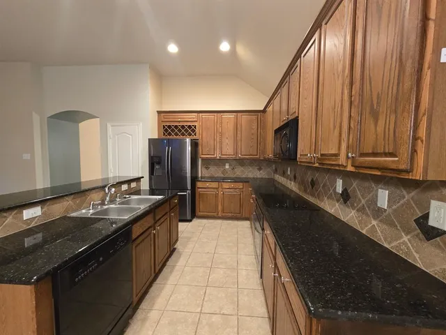 a kitchen with granite countertop stainless steel appliances a sink stove top oven and cabinets