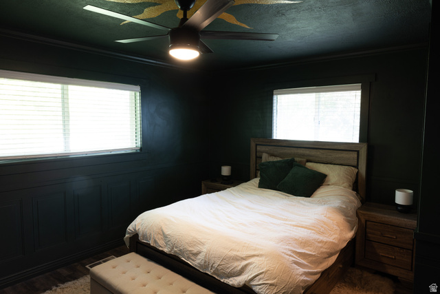 827 South 600 East Logan, UT 84321 - Photo 20 of 30 Dark-toned room featuring two windows with horizontal blinds, wall paneling, and a ceiling fan with integrated lighting