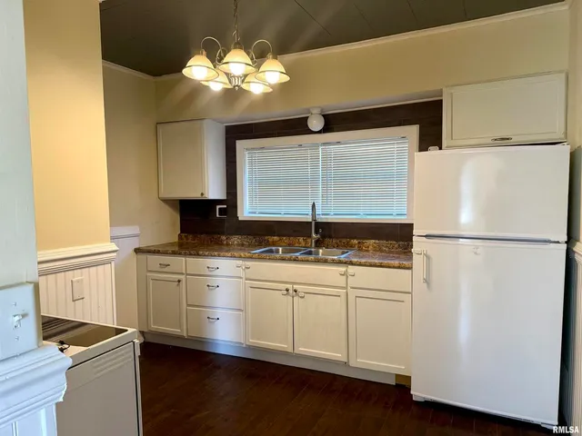 a kitchen with stainless steel appliances granite countertop a sink a stove a refrigerator and island with wooden floor